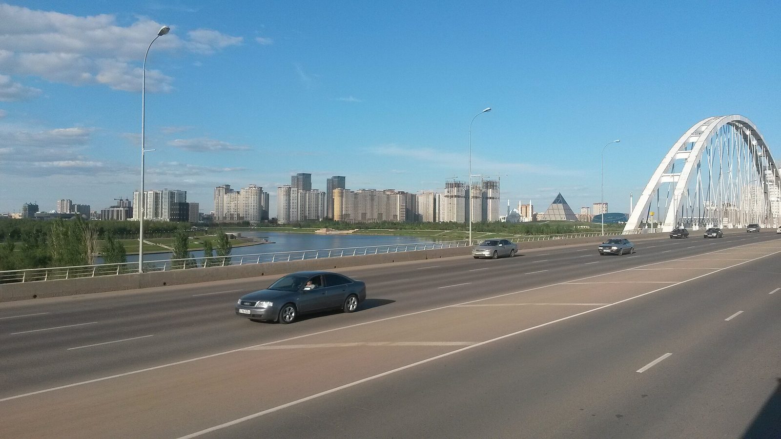 Проспект в Астане с аркой моста и жилыми кварталами на горизонте