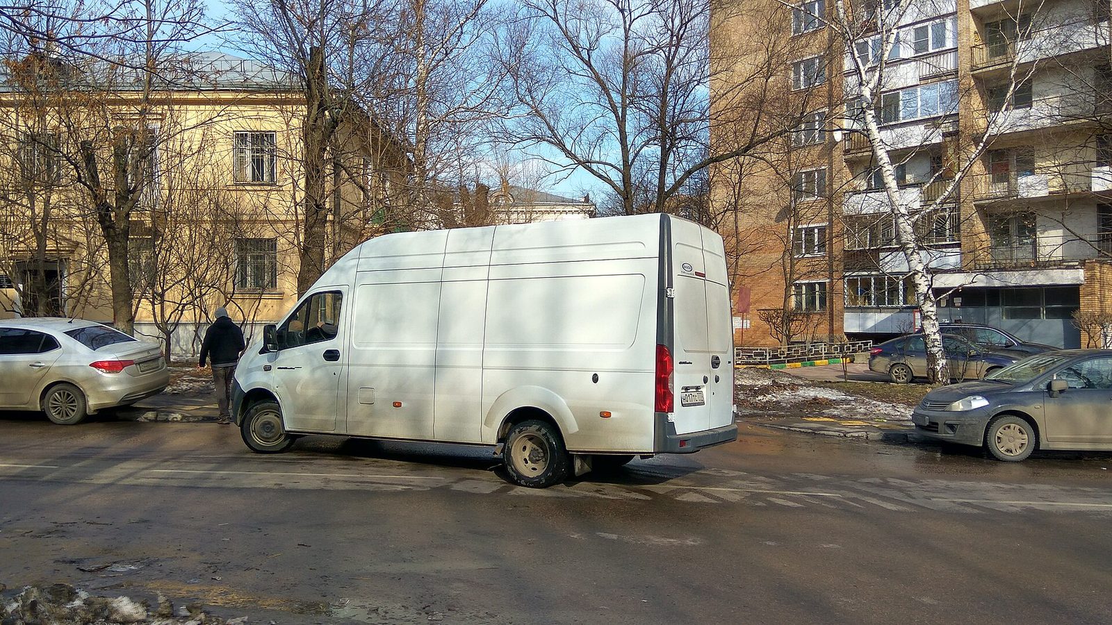 Белый фургон ГАЗель Next разворачивается на городской улице